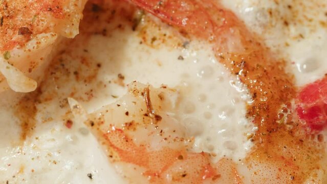 Shrimps in a creamy sauce with garlic and lime juice are languishing in a frying pan. Traditional Asian Mexican Thai dish. High quality studio shot macro close-up. Cooking Italian
