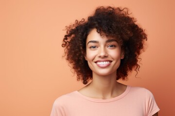 closeup portrait of young happy woman looking in camera on peach fuzz background