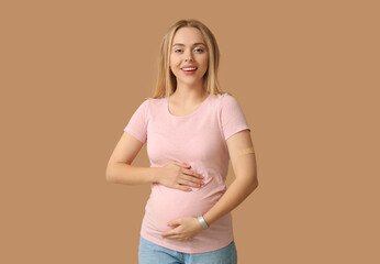 Young pregnant woman after vaccination on beige background