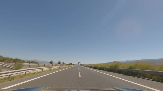First person view, FPV, from dashcam of car driving fast on the highway towards the Tabernas desert in Almeria, Andalusia, Spain, Europe. Road trip video in POV, with bright, sunny, clear sky