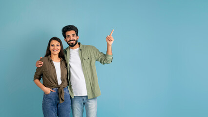 Positive indian couple showing blank space for advertisement - Powered by Adobe