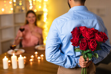 Surprised woman with wine as man approaches with roses