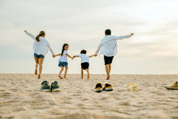 Back view of family parents with children fun holding hands together running to beach in holiday,...
