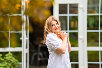 an attractive woman in a white summer dress on the threshold of a country house