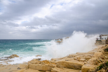 Rocky shore against a cloudy sky and waves in the sea. Malta