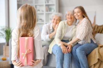 Little girl with gift for her family at home, back view