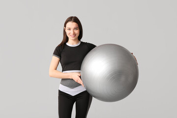 Fototapeta premium Sporty young woman with fitball on light background
