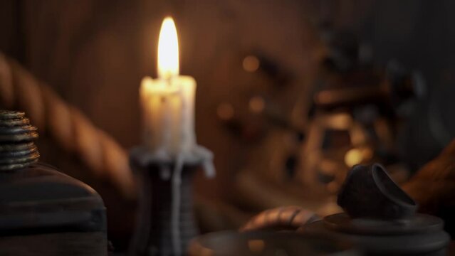 Dolly shot of antique burning candle with vintage sextant, rope and other marine accessories. Sea adventure concept. Selective focus, low shallow focus