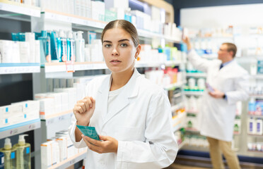 Girl pharmacist carefully reads the information on the label of a medicinal intimate hygiene in a pharmacy