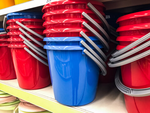 Buckets in the store. Household for mopping floors of blue and red colors, stand in a stack on the rack of a hardware store .concept household goods