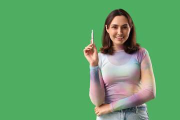 Young woman with electronic cigar on green background