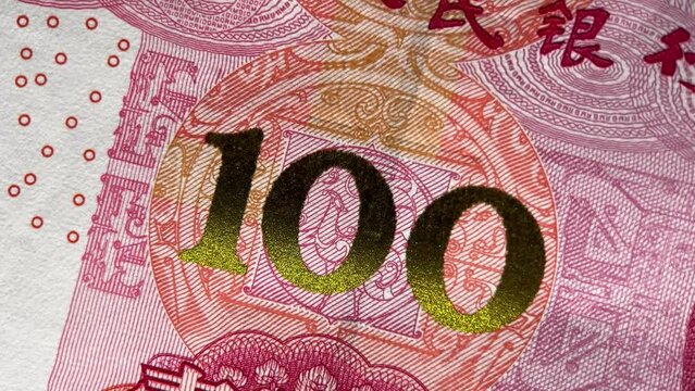 Close-up of a 100 yuan currency note denomination with intricate red and gold patterns, suitable for financial or economic themes