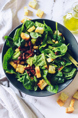 Healthy salad with spinach, croutons, sun-dried tomatoes and black olives