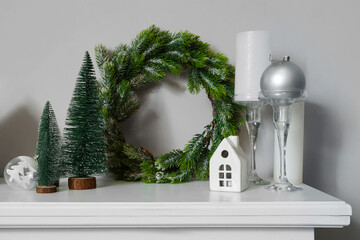 Mantelpiece with Christmas decorations near white wall, closeup