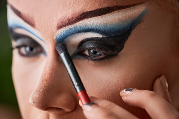 Close up of male performer doing dramatic eye make up, copy space