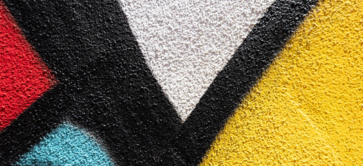 Abstract wall surface with part of graffiti. Geometric lines, light blue, yellow, black, red colors...