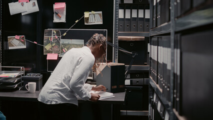 Woman detective uncovering clues on evidence board, working on crime solving in archive room....