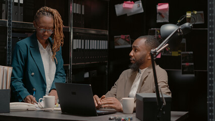 Police investigators reading records for crime case, doing teamwork to find suspect in evidence...