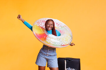 Excited young woman posing in studio with inflatable and suitcase luggage, having fun with journey...