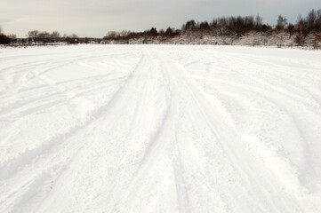 Fototapeta na wymiar snowy road and car wheel marks in winter