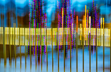 abstract background of blue sky with colored lights of yellow purple and orange colourful Christmas lights blurred from camera motion depicting technology and movement in multi colours intentional cam