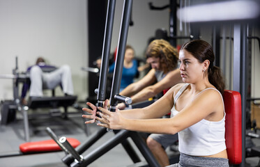 Fototapeta na wymiar Caucasian woman doing exercises on chest fly machine in gym