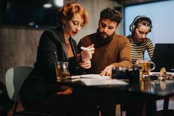 Business people collaborating on data analysis and sales strategy in a corporate office at night...