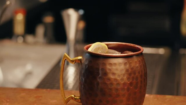 Icy Cold Moscow Mule cocktail with Ginger Beer and Vodka, bartender making cocktail in copper mug.
