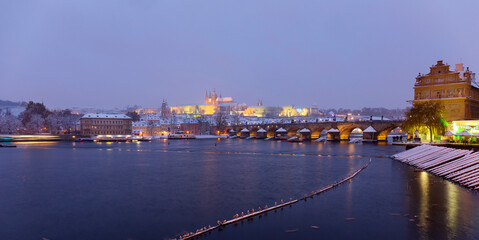 Night snowy Prague Lesser Town with gothic Castle, St. Nicholas' Cathedral and Charles Bridge, Czech republic