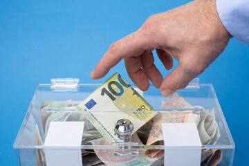 Donating or saving cash money in nominal 100 Euro Eu banknotes, The transparent  charity box...