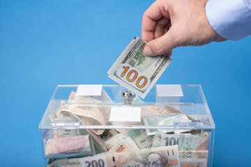 Donating or saving cash money in nominal 100 Dollars USD banknotes, The transparent  charity box...