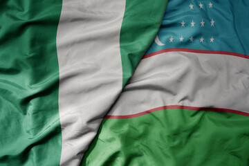 Obraz premium big waving national colorful flag of uzbekistan and national flag of nigeria .