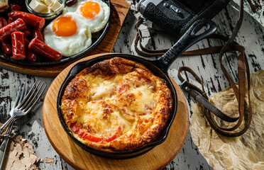 Delicious breakfast, omelette with vegetables and cheese served on hot pan over wooden background. Healthy food breakfast, close up
