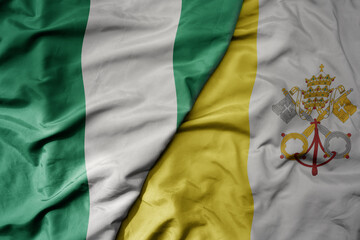 Obraz premium big waving national colorful flag of vatican city and national flag of nigeria .