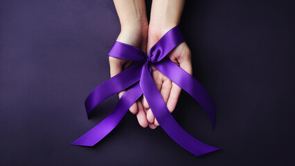 Adult and child hands holding purple ribbons, Alzheimer's disease, Pancreatic cancer.