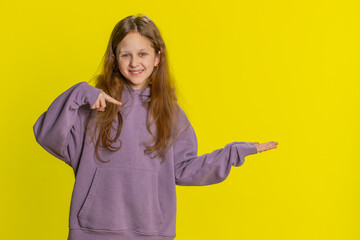 Preteen child girl kid showing thumbs up pointing right empty place, advertising area for commercial discount text, copy space for goods promotion advertisement. Teenager children on yellow background