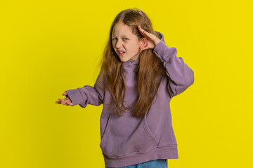 I cant hear you. What. Child girl kid trying hear you, looking confused and frowning, keeping arm near ear for louder voice asking to repeat to hear information deafness. Children on yellow background - obrazy, fototapety, plakaty
