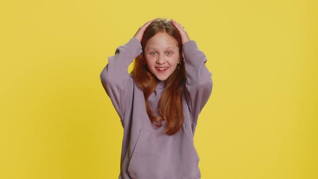 Oh my God, Wow. Young preteen child girl kid looking surprised at camera with big eyes, shocked by sudden victory game winning lottery goal achievemen good news. Children isolated on yellow background