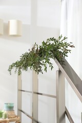 Beautiful garland made of eucalyptus branches on handrail indoors