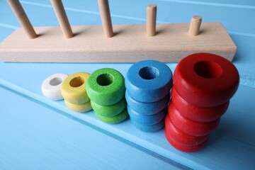 Stacking and counting game pieces on light blue wooden table, closeup. Motor skills development