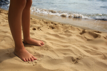 Little girl standing on sandy beach, closeup. Space for text - Powered by Adobe