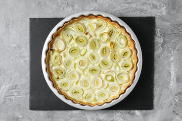 Freshly baked leek pie on grey textured table, top view
