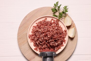 Obraz na płótnie Canvas Manual meat grinder with beef mince, onion and parsley on white wooden table, top view