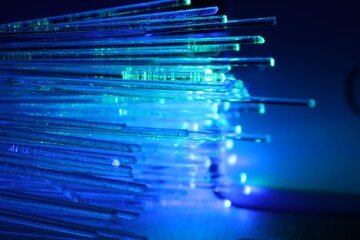 Optical fiber strands transmitting different color lights against blurred background, macro view