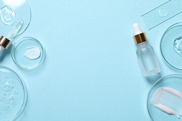 Bottle of cosmetic serum and petri dishes with samples on light blue background, flat lay. Space...