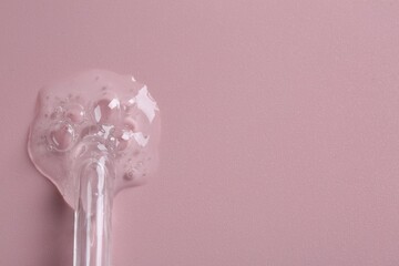 Pipette with cosmetic serum on pink background, top view. Space for text