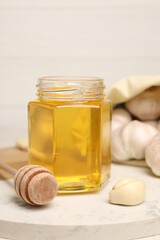 Jar with honey, garlic and dipper on board, closeup