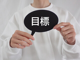 目標と書いてある吹き出しを若い男性が持っている