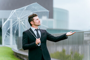 梅雨・台風の雨でビニール傘をさす外国人ビジネスマン
