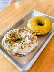 Two glazed donuts on silver platter